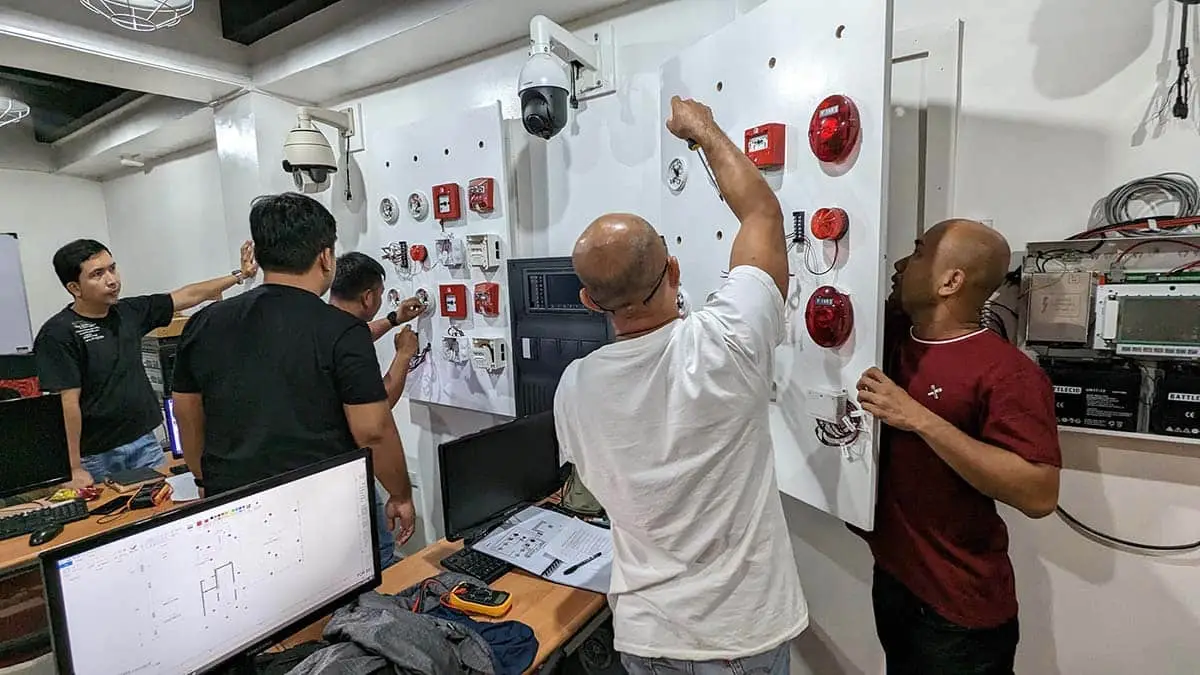 Students working on FDAS control panels during practical training in the Philippines