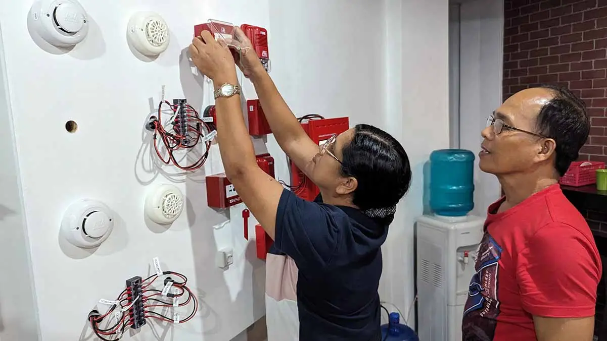 Close-up of trainees working on FDAS wiring connections under the supervision of an expert