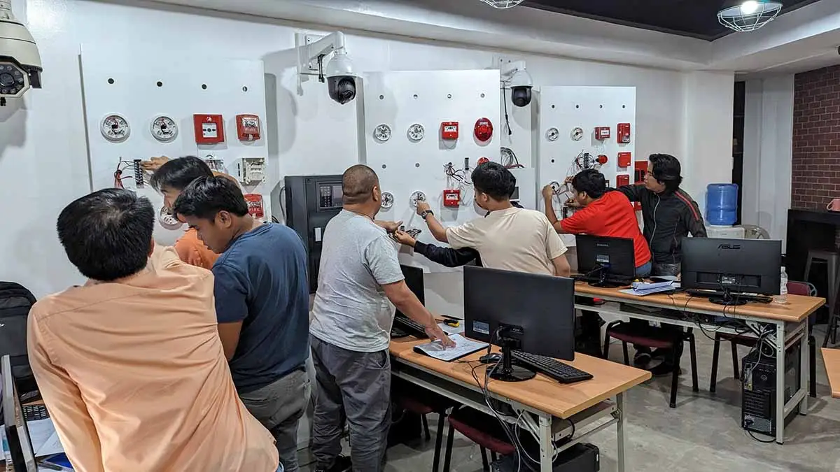 Trainees working on FDAS wiring and panel installation during a workshop in the Philippines